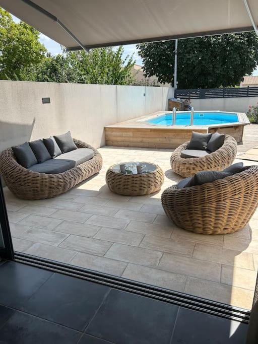 - une terrasse avec des canapés et des chaises à côté de la piscine dans l'établissement Maison de charme avec piscine, à Aigrefeuille-dʼAunis