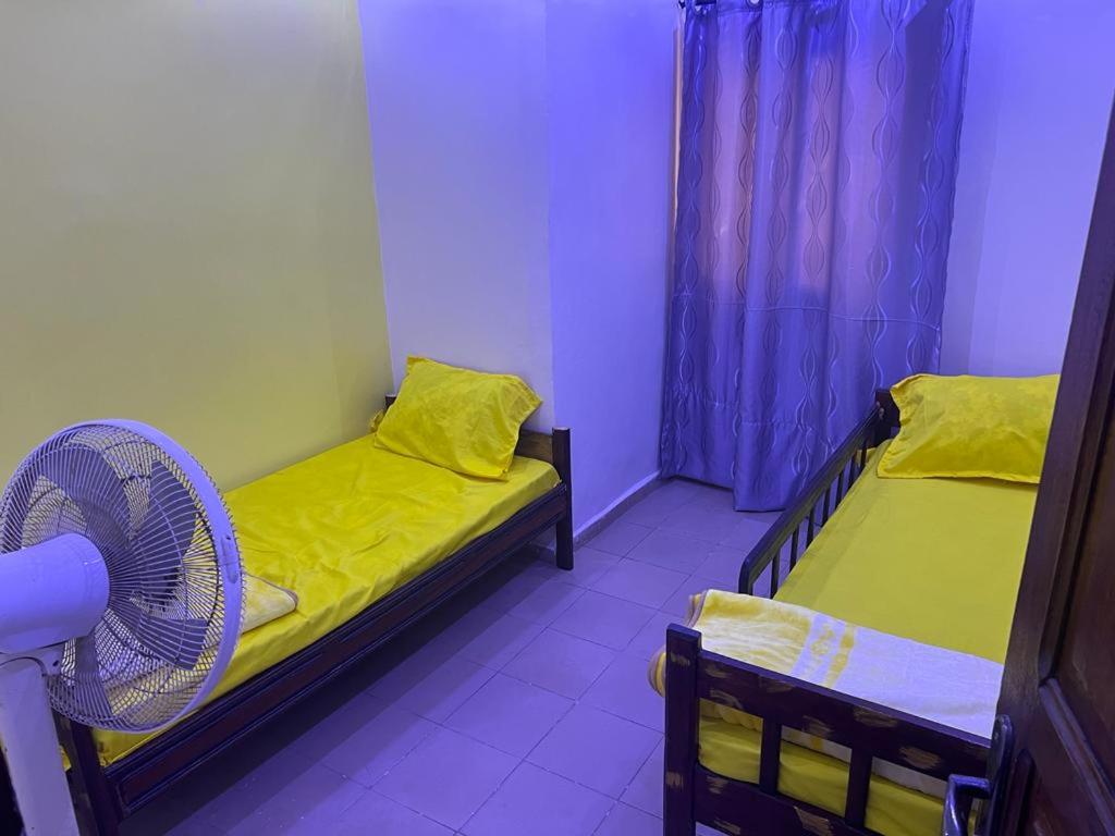 a small room with two beds and a fan at T3 meublé Chez Diouma in Dakar