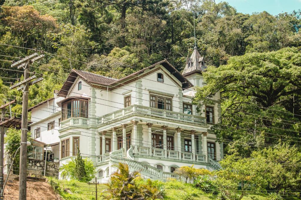 una vieja casa blanca en una colina con árboles en Pousada Casa Imperatriz - Rua Teresa, en Petrópolis