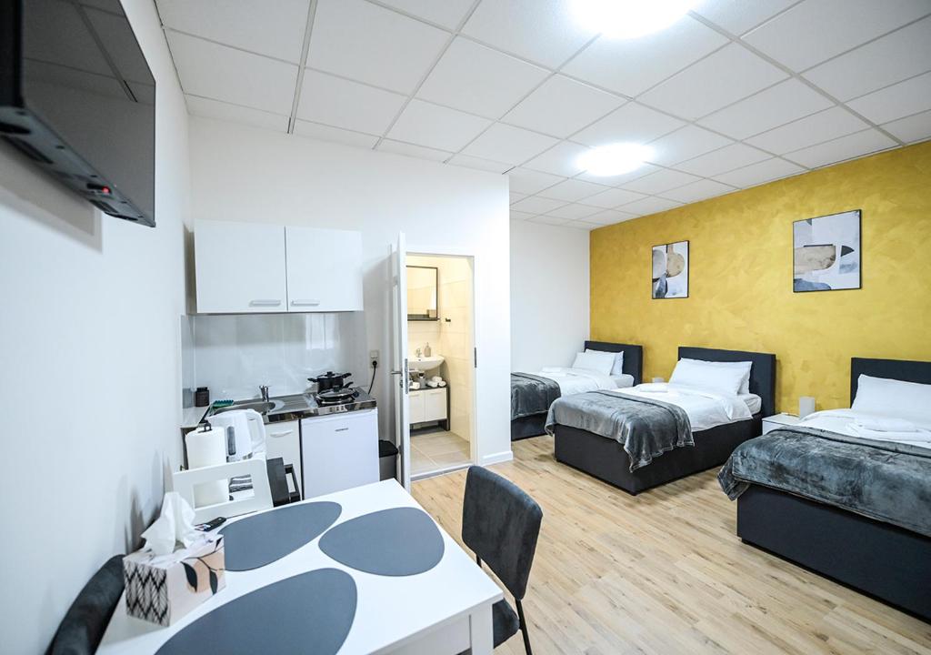 a room with two beds and a table and a kitchen at GLOW Apartment in Magdeburg