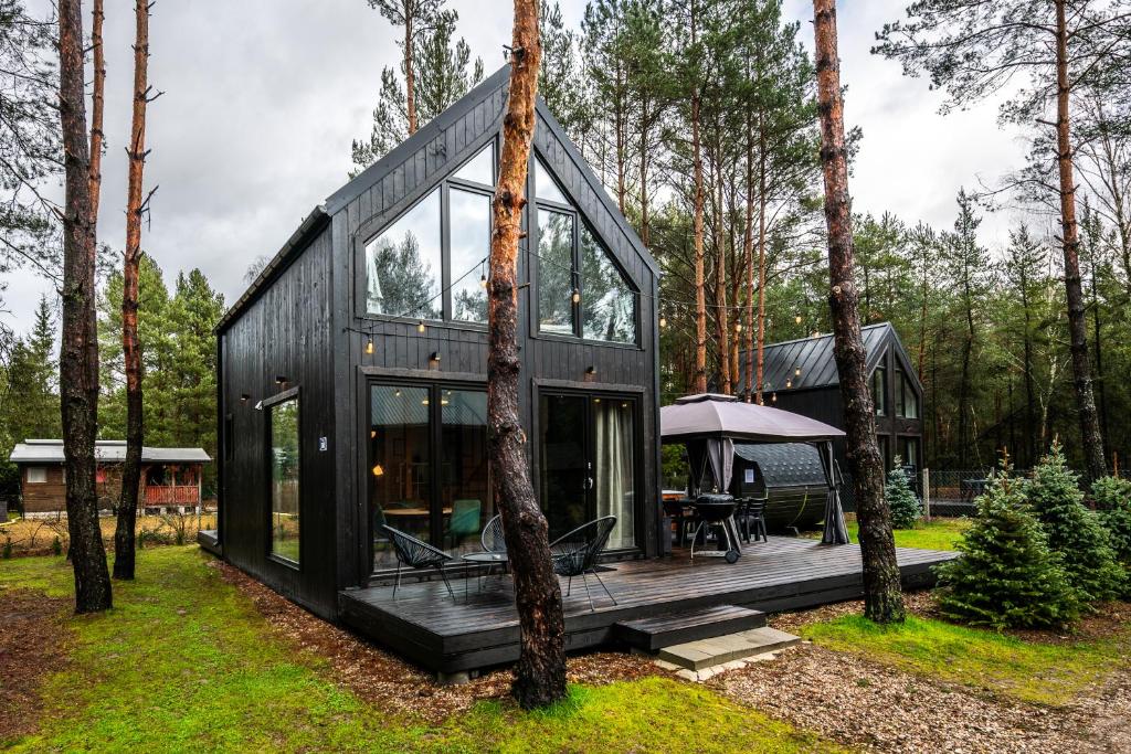 a black house in the middle of a forest at Heban Forest Cabin&SAUNA Starlink in Tomczyn