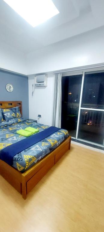een slaapkamer met een bed en een groot raam bij 2BR, BIG & COZY UNIT 592sqft at TORRE DE MANILA in Manilla