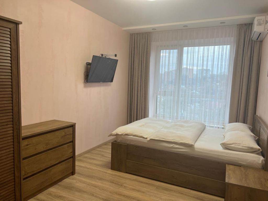 a bedroom with a bed and a window with a television at Goldenhaus Pushkina str.27 in Vinnytsya