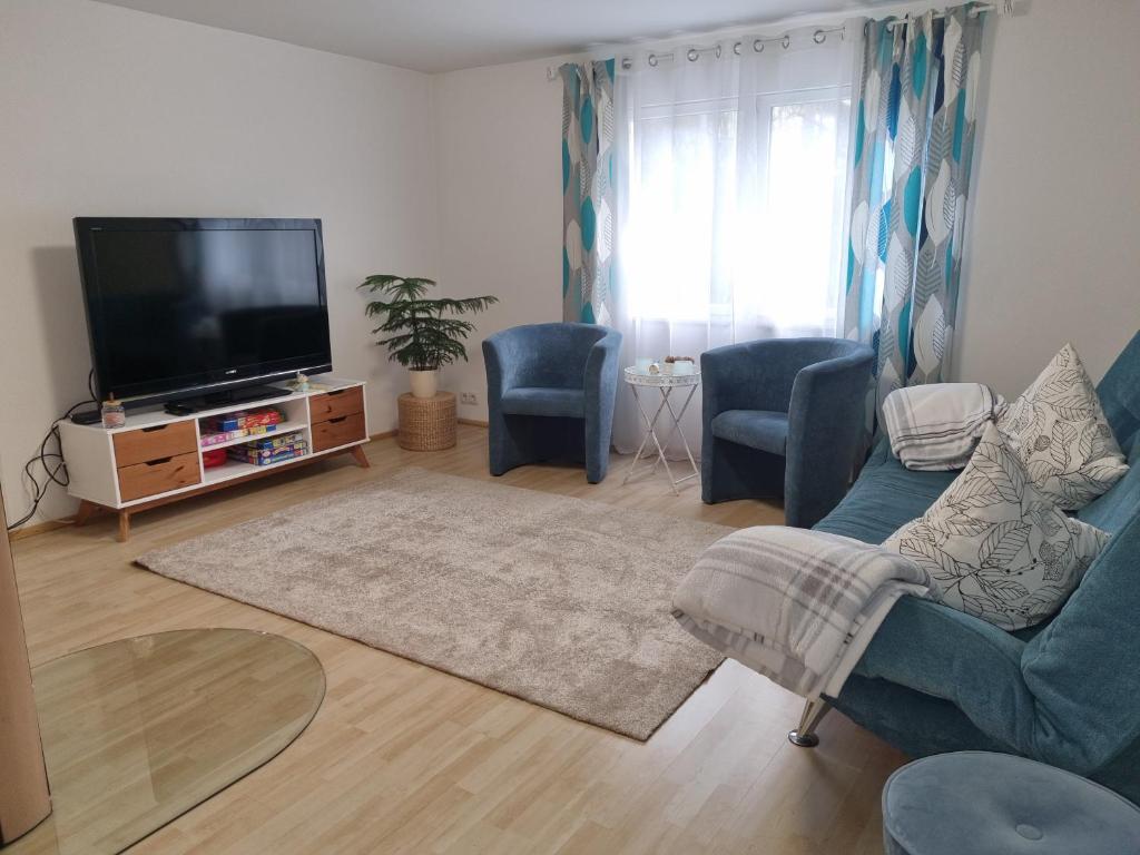 a living room with a flat screen tv and blue chairs at Ferienhaus Alexandra in Böllenborn