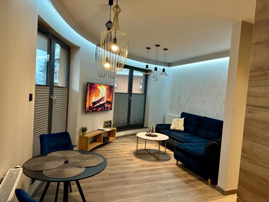 Beautiful Apartment Tarasy Wiślane Free GARAGE في كراكوف: غرفة معيشة مع أريكة زرقاء وطاولة