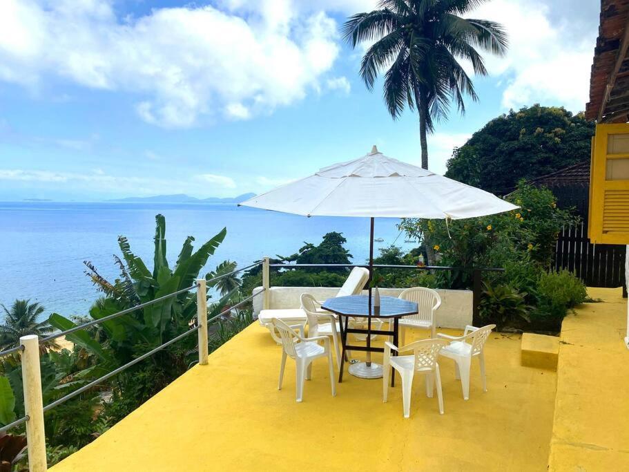 een patio met een tafel en stoelen en een parasol bij Casa del Artista, Ilha Grande Araçatiba in Angra dos Reis