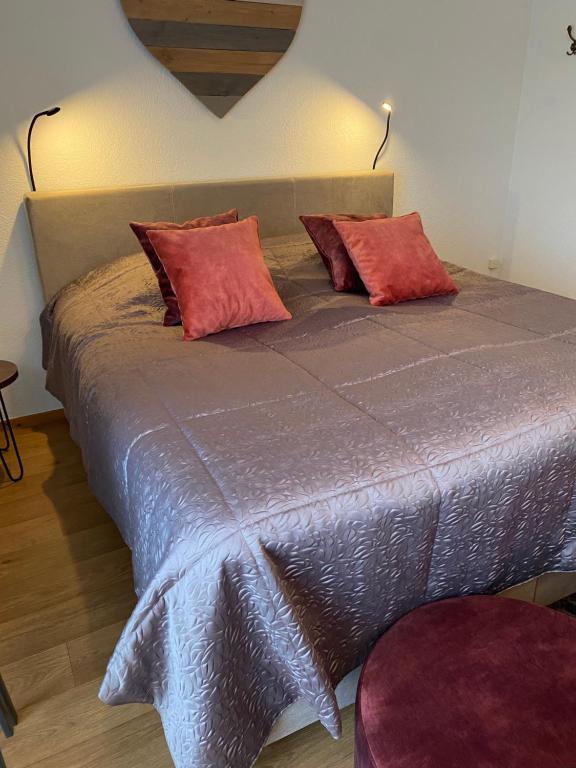 a bed with red pillows on it in a room at Hotelkamer Bellevue in Simpelveld