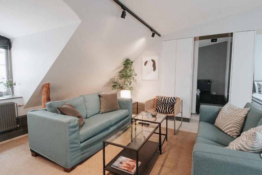 una sala de estar con 2 sofás azules y una mesa. en Guldgränd en Estocolmo