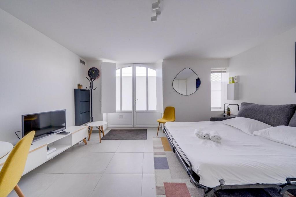 une chambre blanche avec un lit et une télévision dans l'établissement Very lovely apartment Bordeaux, à Bordeaux