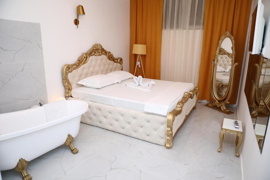 een slaapkamer met een bed, een bad en een spiegel bij Hotel Gloria KS in Pristina