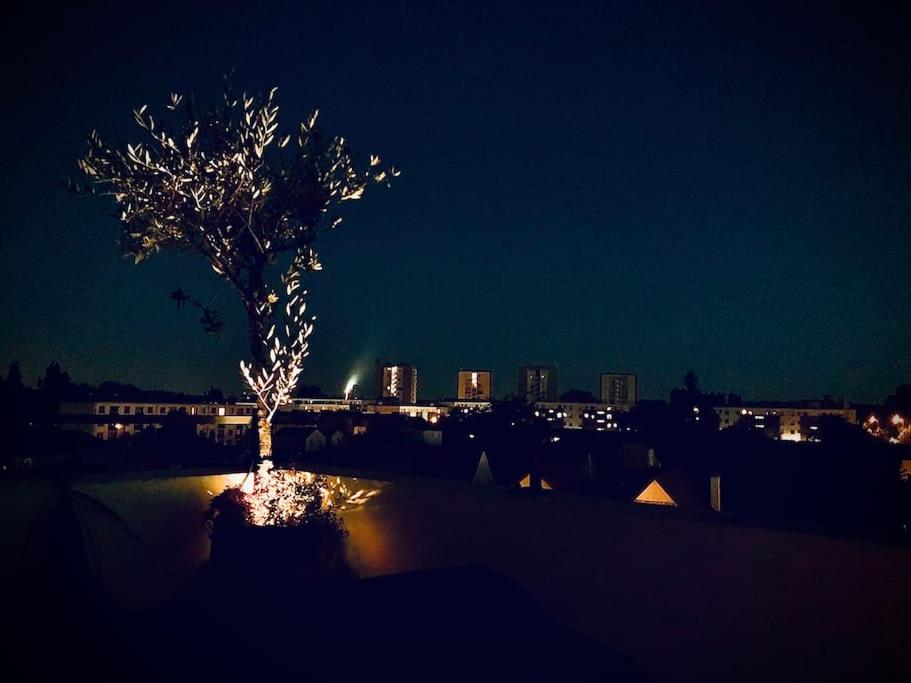 un árbol iluminado por la noche con una ciudad en Apt w/ view on the Eiffel Tower, en Soisy-sous-Montmorency