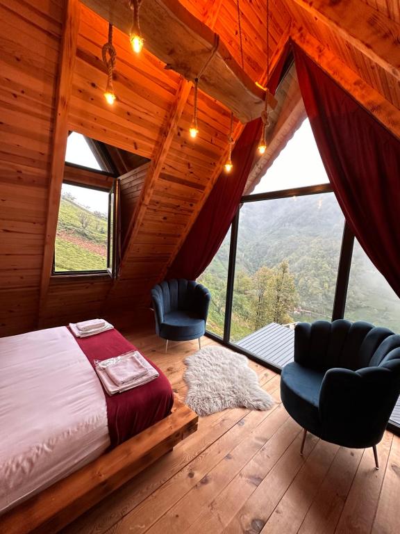ein Schlafzimmer mit einem Bett und zwei Stühlen in einer Hütte in der Unterkunft OTANİ DAĞ EVLERİ in Çamlıhemşin