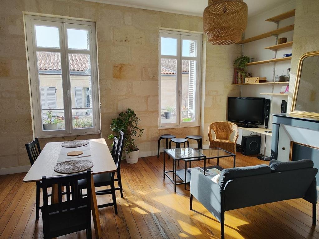ein Wohnzimmer mit einem Tisch, Stühlen und einem TV in der Unterkunft Charming apartment Bordeaux center in Bordeaux