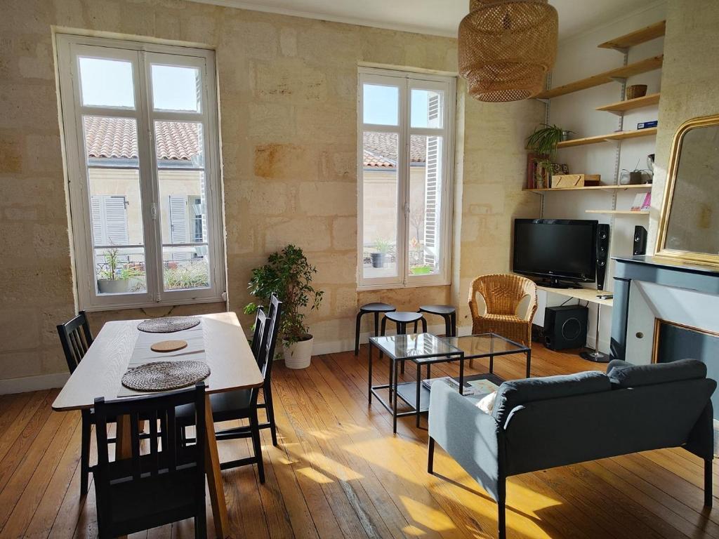 un salon avec une table, des chaises et une télévision dans l'établissement Charming apartment Bordeaux center, à Bordeaux