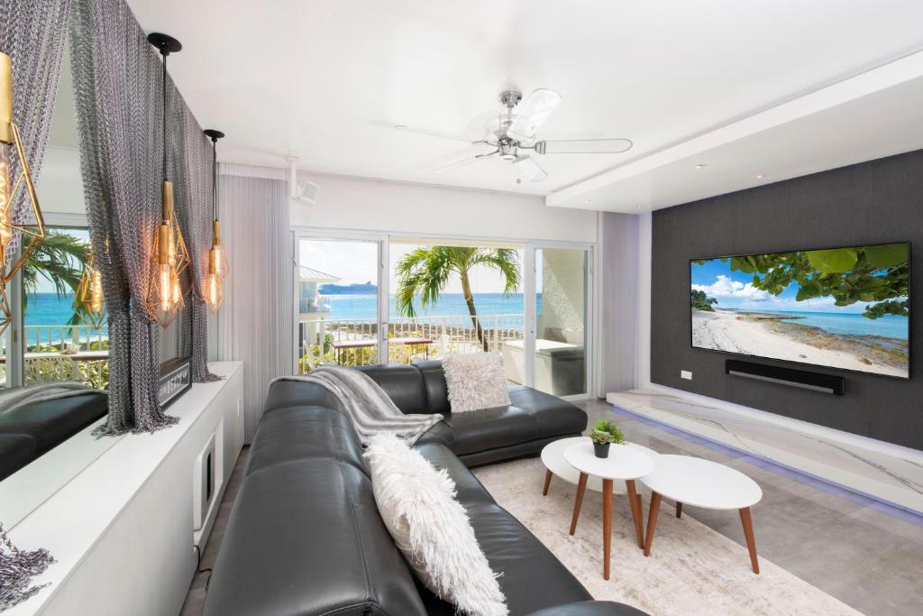 a living room with a black leather couch and a tv at Grape Tree Condo #10 in George Town