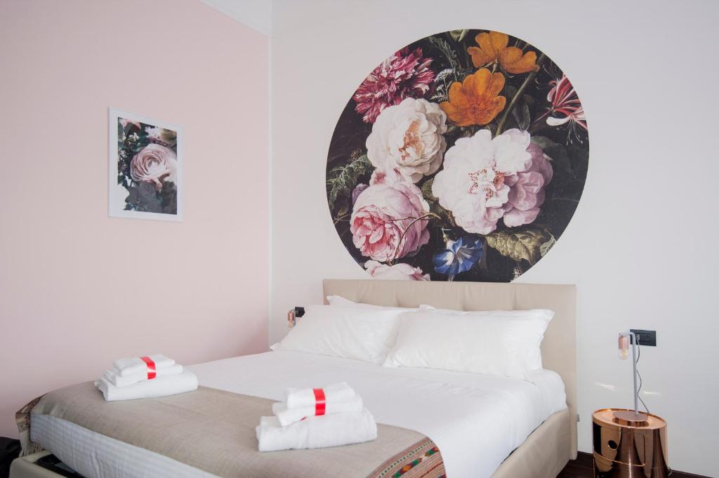 1 dormitorio con 1 cama con una pintura floral en la pared en DUOMO VIEW - 2 min from Duomo Amazing location, en Milán