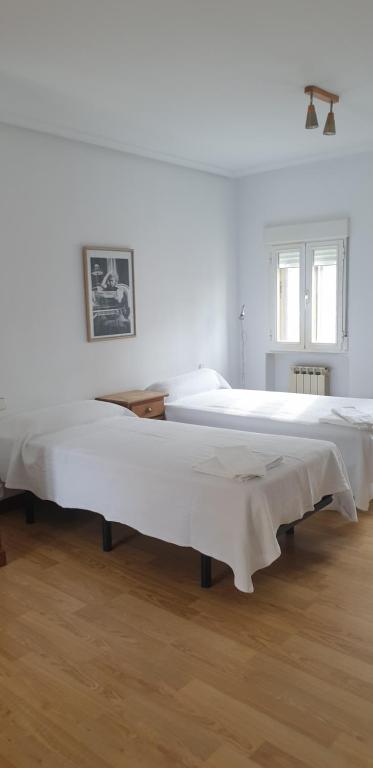 Casa Telares Ávila في أفيلا: سريرين في غرفة بجدران بيضاء وأرضية خشبية