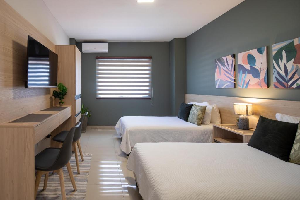 a hotel room with two beds and a desk at Equipetrol Suites apart hotel in Santa Cruz de la Sierra