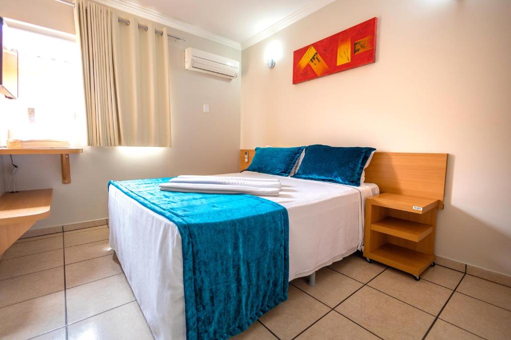 - une chambre avec un lit et des oreillers bleus dans l'établissement DiRoma Fiori Hotel - BVTUR, à Caldas Novas