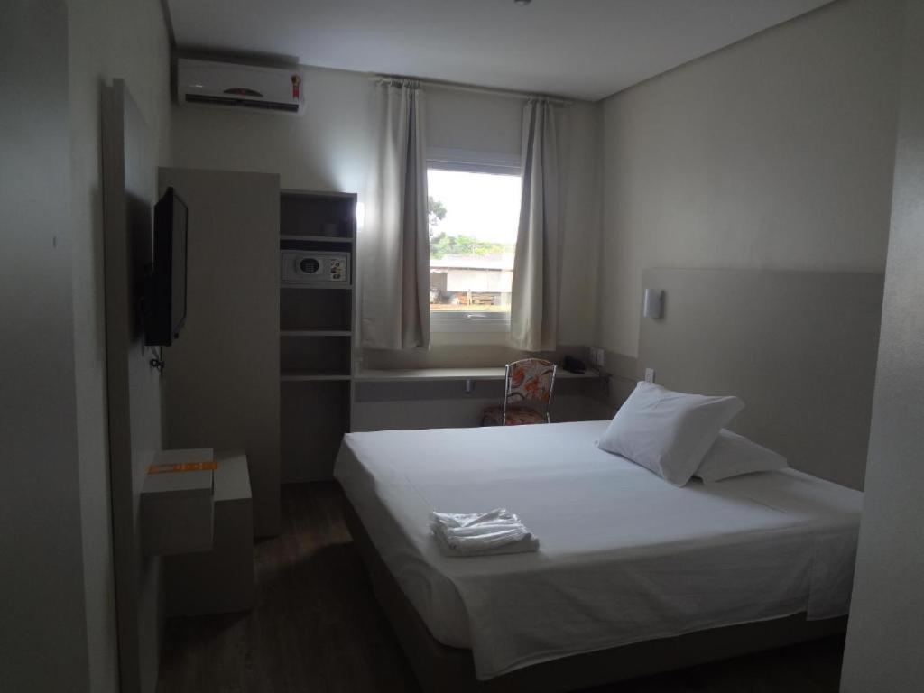 a bedroom with a white bed and a window at DE STEFANI HOTEL in Portão