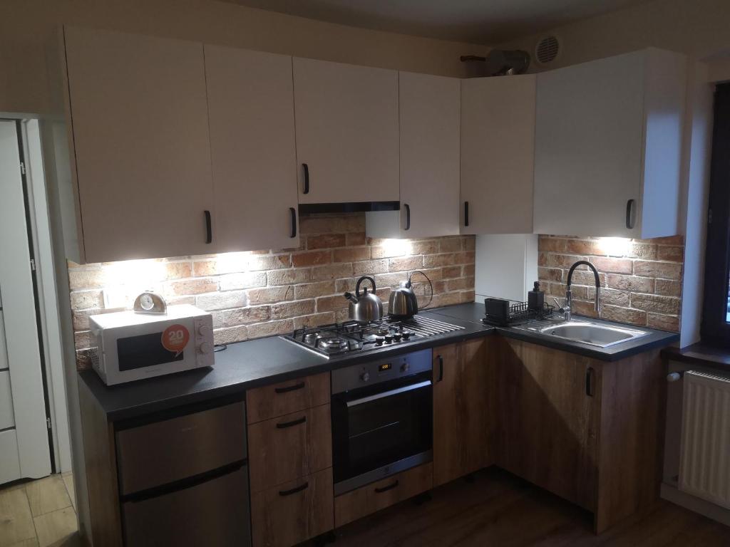 a kitchen with white cabinets and a stove and a microwave at apartament Stary Piec Jedlina Zdrój in Jedlina-Zdrój