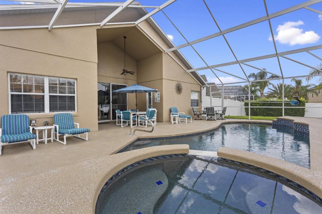 una piscina con sillas, una mesa y una sombrilla en Family Home 5mi to Disney: Pool & Game Room, en Orlando