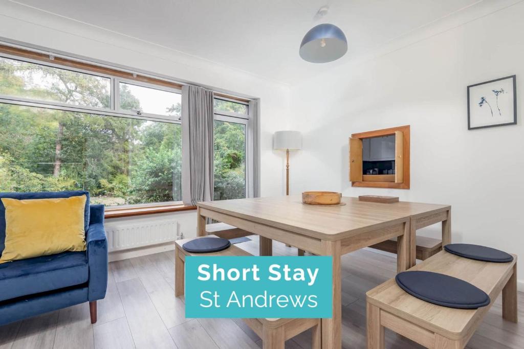 een woonkamer met een houten tafel en een blauwe stoel bij Greentiles - Spacious House - Extensive Garden - Convenient Location in St Andrews