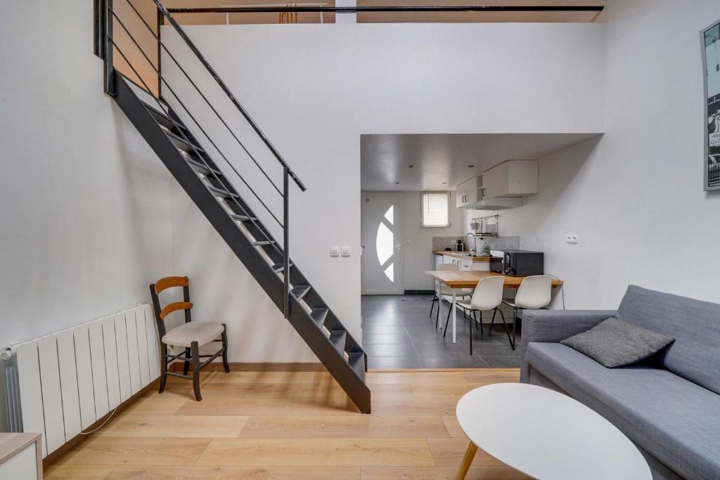 una sala de estar y comedor con una escalera en un loft en Charmante petite maison de ville Bordeaux, Talence, en Talence