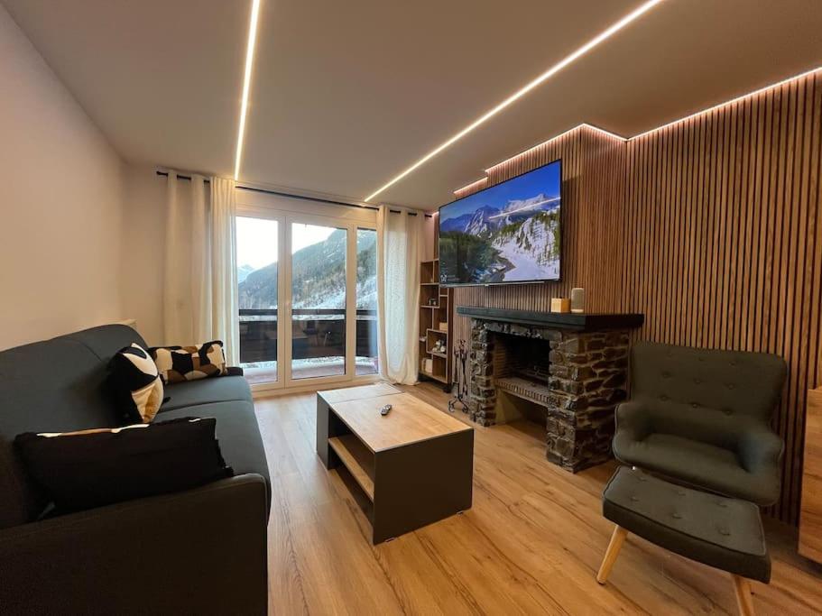 een woonkamer met een bank, een open haard en een televisie bij 6. APT Encantador en Arinsal in Arinsal