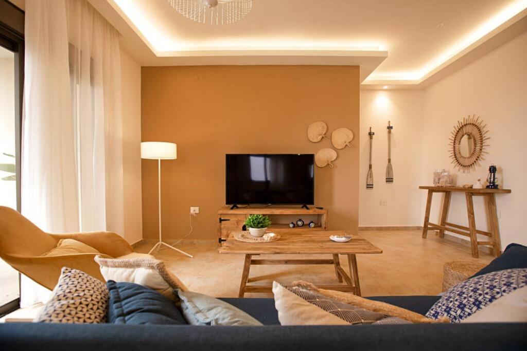 uma sala de estar com um sofá e uma televisão em Denis 2BR Apartment in Batroun em Batroûn