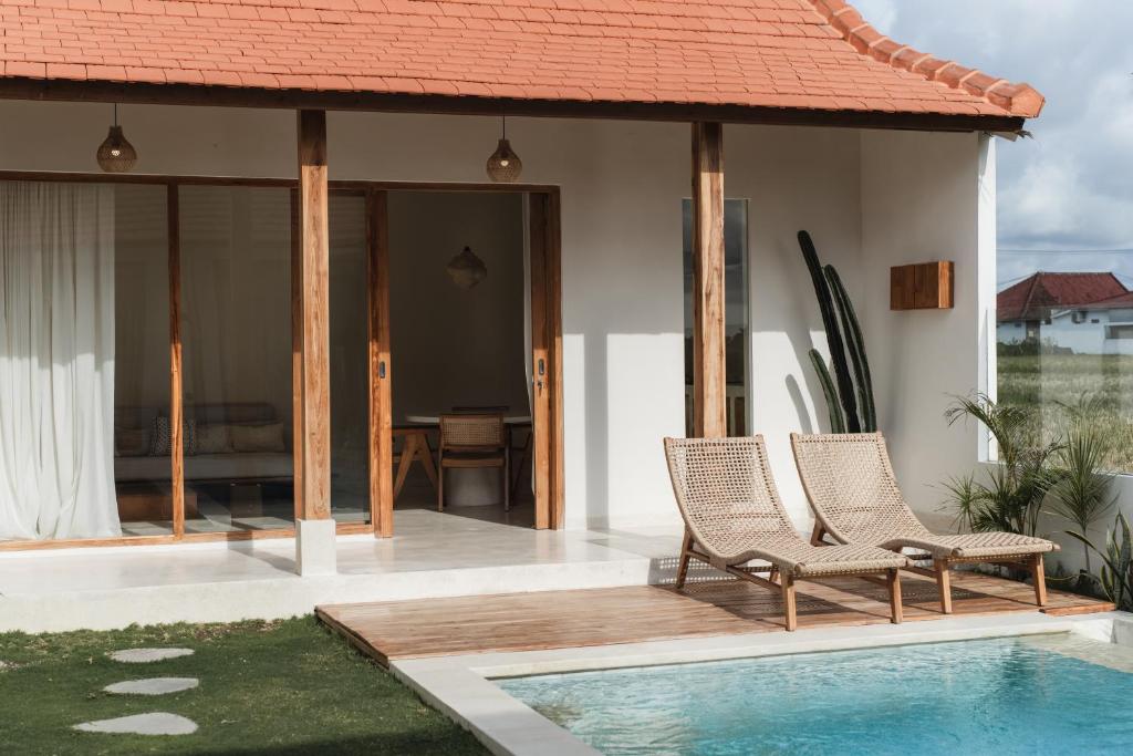 a villa with a swimming pool and two chairs at Villa FES 2 Bedrooms Private Villa 5mins Beach in Munggu