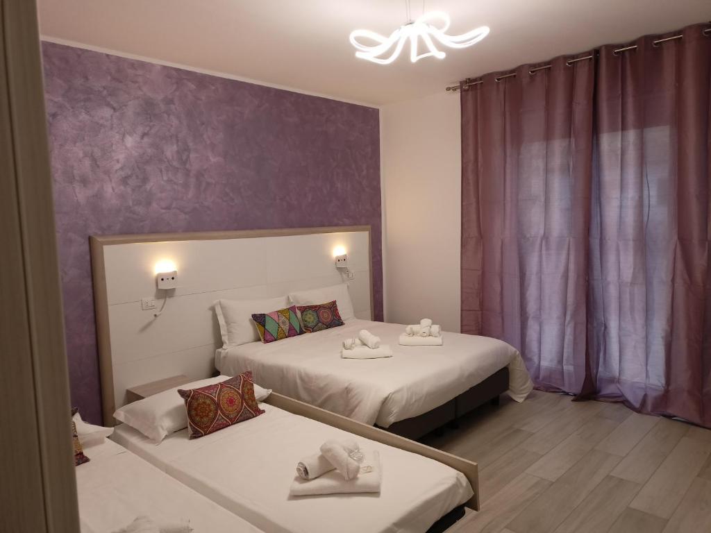 - une chambre avec 2 lits et un mur violet dans l'établissement La Dea Rooms, à Ferrare