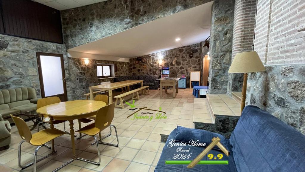 un soggiorno con pareti in pietra, tavolo e sedie di Casa Rural Juanín - Alojamiento Turístico Gold a Fresnedoso de Ibor