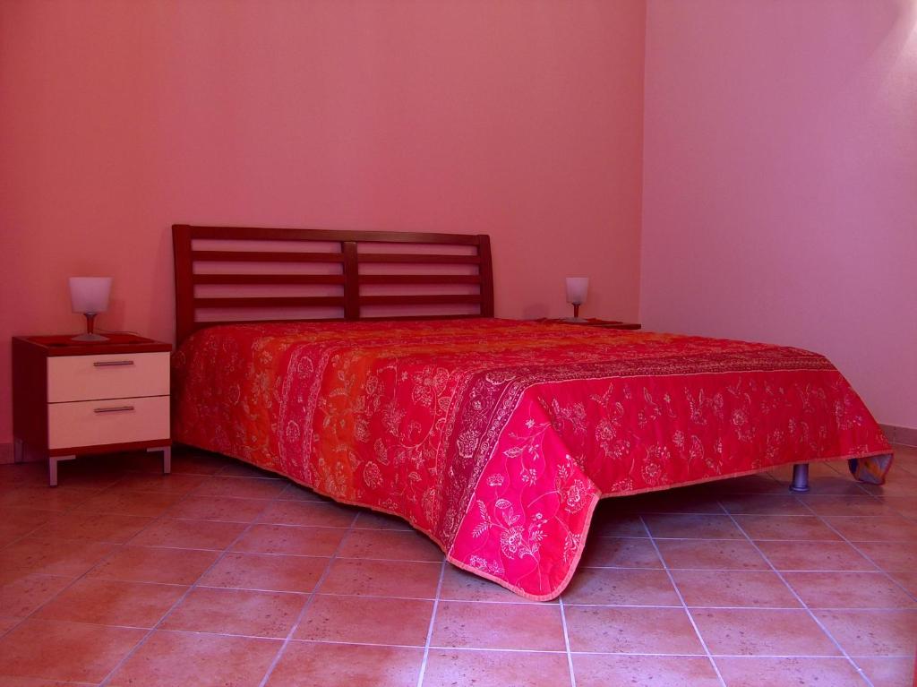 a bedroom with a bed with a red bedspread and a night stand at Casale Vacanze in Siculiana
