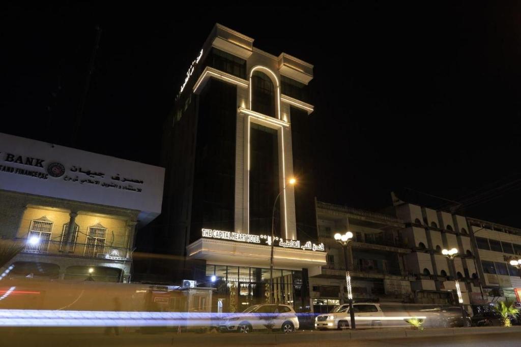 a large building with a tall tower at night at The Capital Heart Hotel in Baghdad