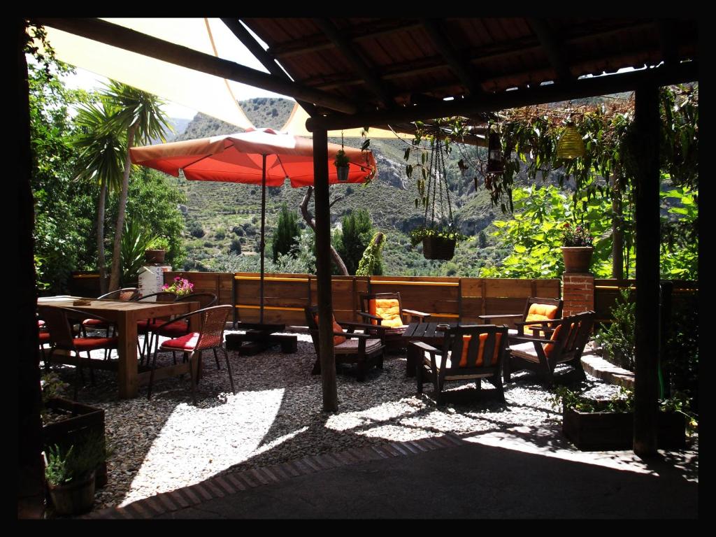 eine Terrasse mit einem Tisch, Stühlen und einem Sonnenschirm in der Unterkunft Fundalucia in Quéntar