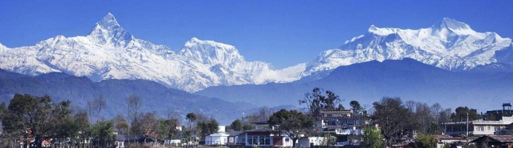 un grupo de montañas cubiertas de nieve con casas y edificios en Hotel Pacific Pokhara, en Pokhara