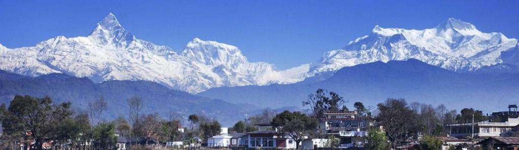 a group of snow covered mountains with houses and buildings at Hotel Pacific Pokhara in Pokhara