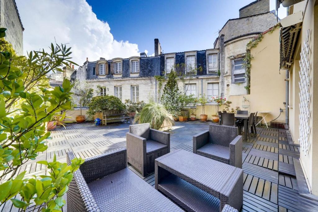 a patio with chairs and tables in front of a building at Lovely apartment with exceptional terrace in Bordeaux