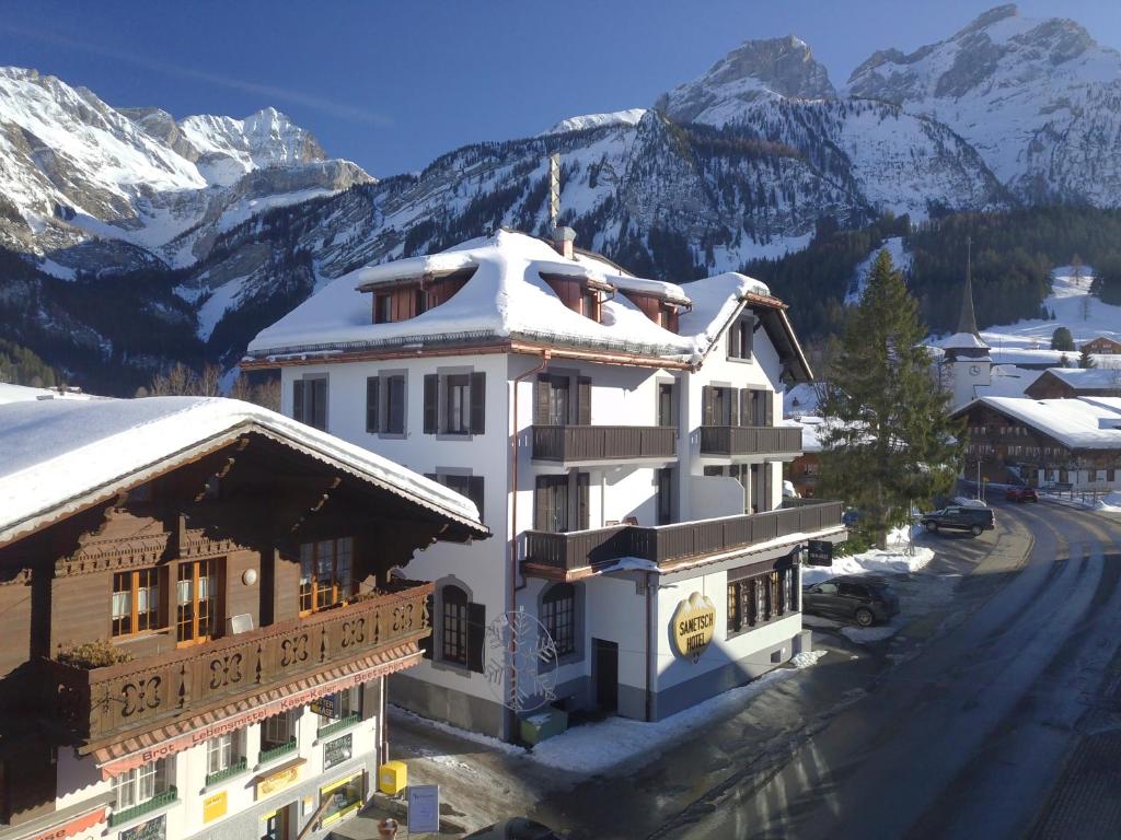 ein weißes Gebäude mit schneebedeckten Bergen im Hintergrund in der Unterkunft Hotel Sanetsch in Gsteig