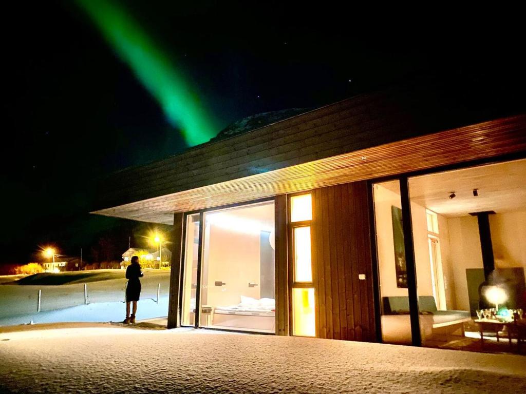 a person standing in front of a building with a green light at Exclusive Beach House Ramberg - Your Private Oasis in Ramberg