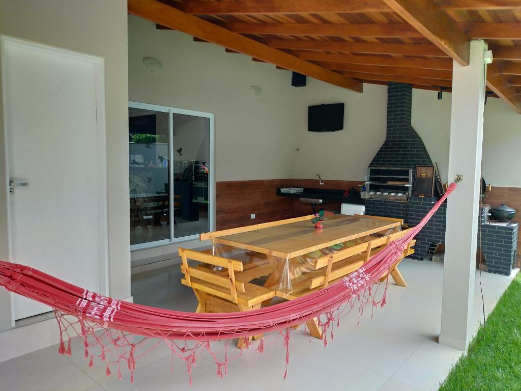 eine Hängematte in einem Haus mit einem Tisch und einem Kamin in der Unterkunft Casa ampla com fácil acesso as Praias e Shopping in Caraguatatuba