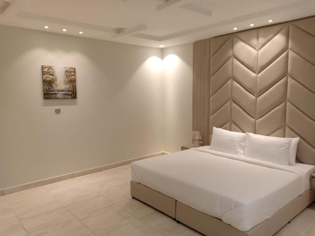 a bedroom with a large white bed and a wall at Dorm Story For Hotel Apartment in Taif