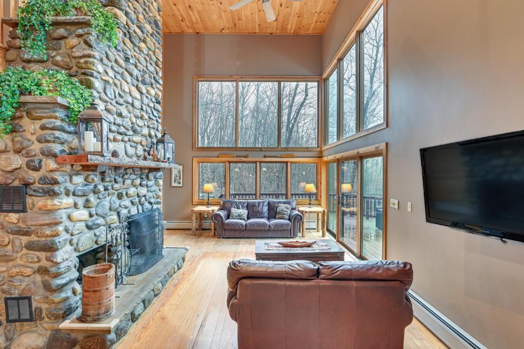 a living room with a stone fireplace and a tv at Secluded Adirondack Cabin about 5 Mi to Sacandaga Lake in Broadalbin