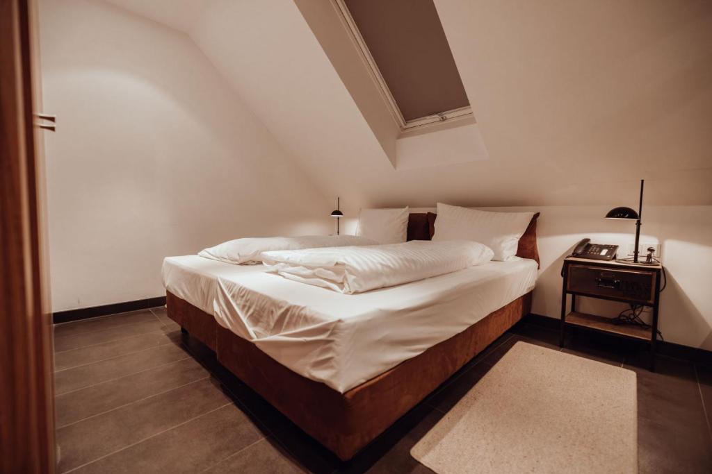 1 dormitorio con 1 cama con sábanas blancas y mesa en Encanto Hotel Restaurant, en Balingen
