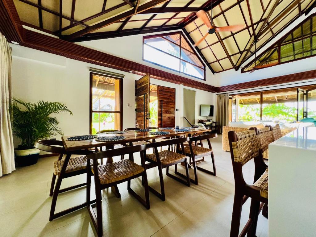 a dining room with a large wooden table and chairs at Sandy Feet Siargao in General Luna