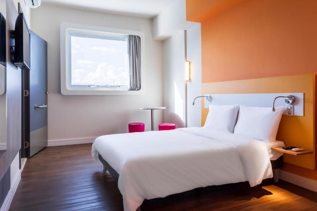 Pokój hotelowy z białym łóżkiem i oknem w obiekcie ibis budget Pindamonhangaba w mieście Pindamonhangaba