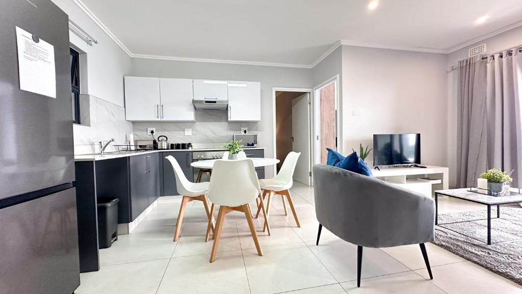 Una cocina y un comedor con mesa y sillas. en Umhlanga Cosy Apartment, en Durban