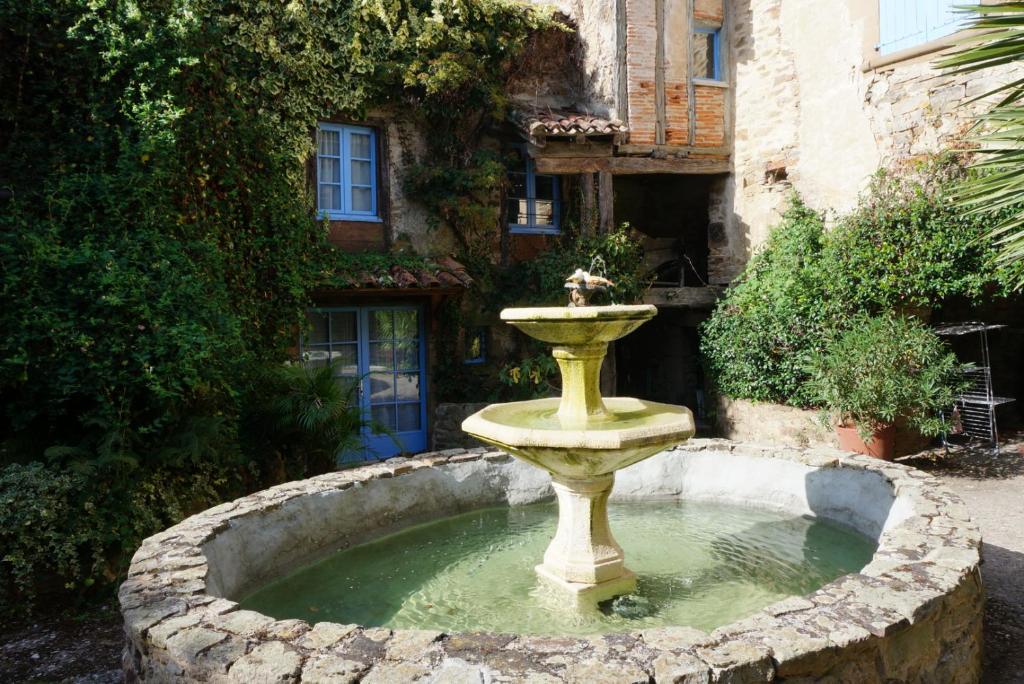a fountain in front of a building at Gite Les Volets Bleus du Segur in Le Ségur-Suech
