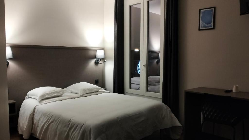 a bedroom with a white bed and a mirror at HÔTEL ROYAL MONTREUIL in Montreuil